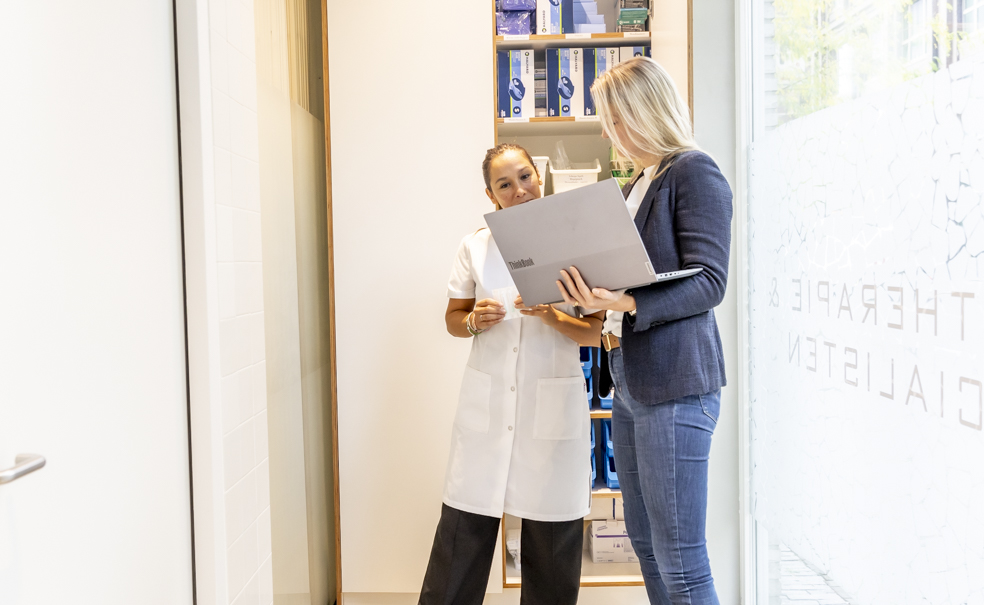 Auditor Lairesse Ziekenhuisfarmacie in gesprek met apothekersassistent over farmaceutische kwaliteitsdocumenten.